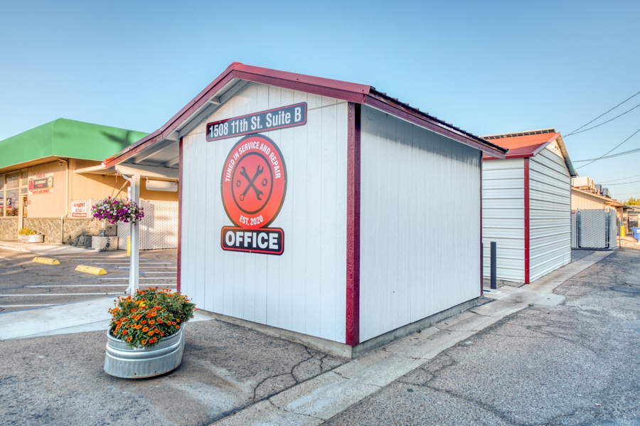 custom logo on side of tan and red trimmed shed with overhang