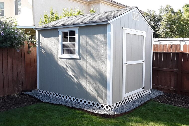 gray and white trimmed shed on a gravel pad