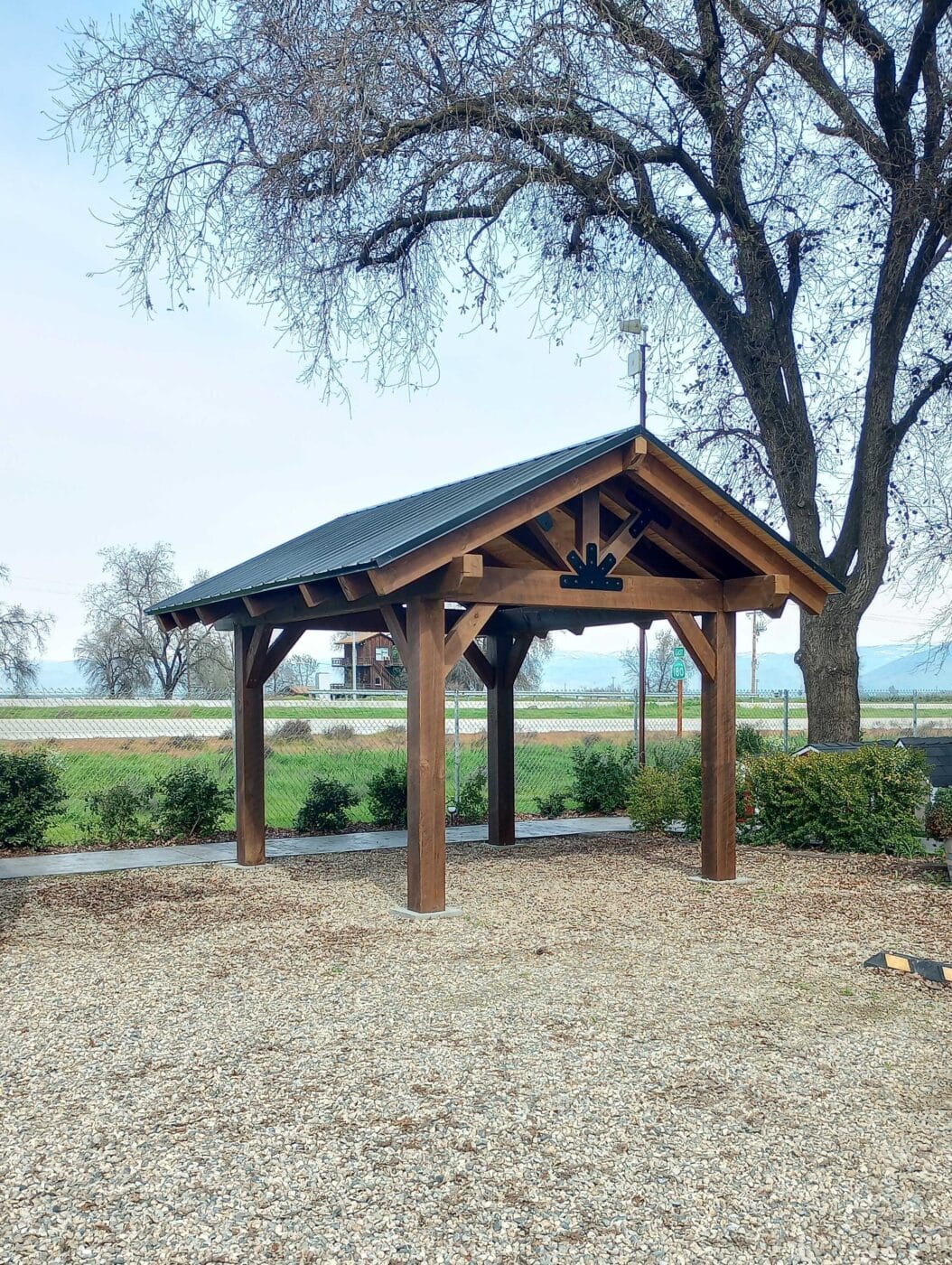 timber frame pavilion with black metal roof in mulch